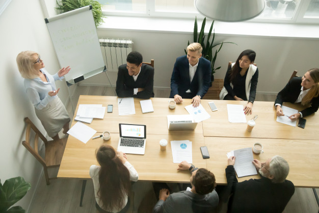Aged senior businesswoman giving presentation at multiracial group office meeting Free Photo